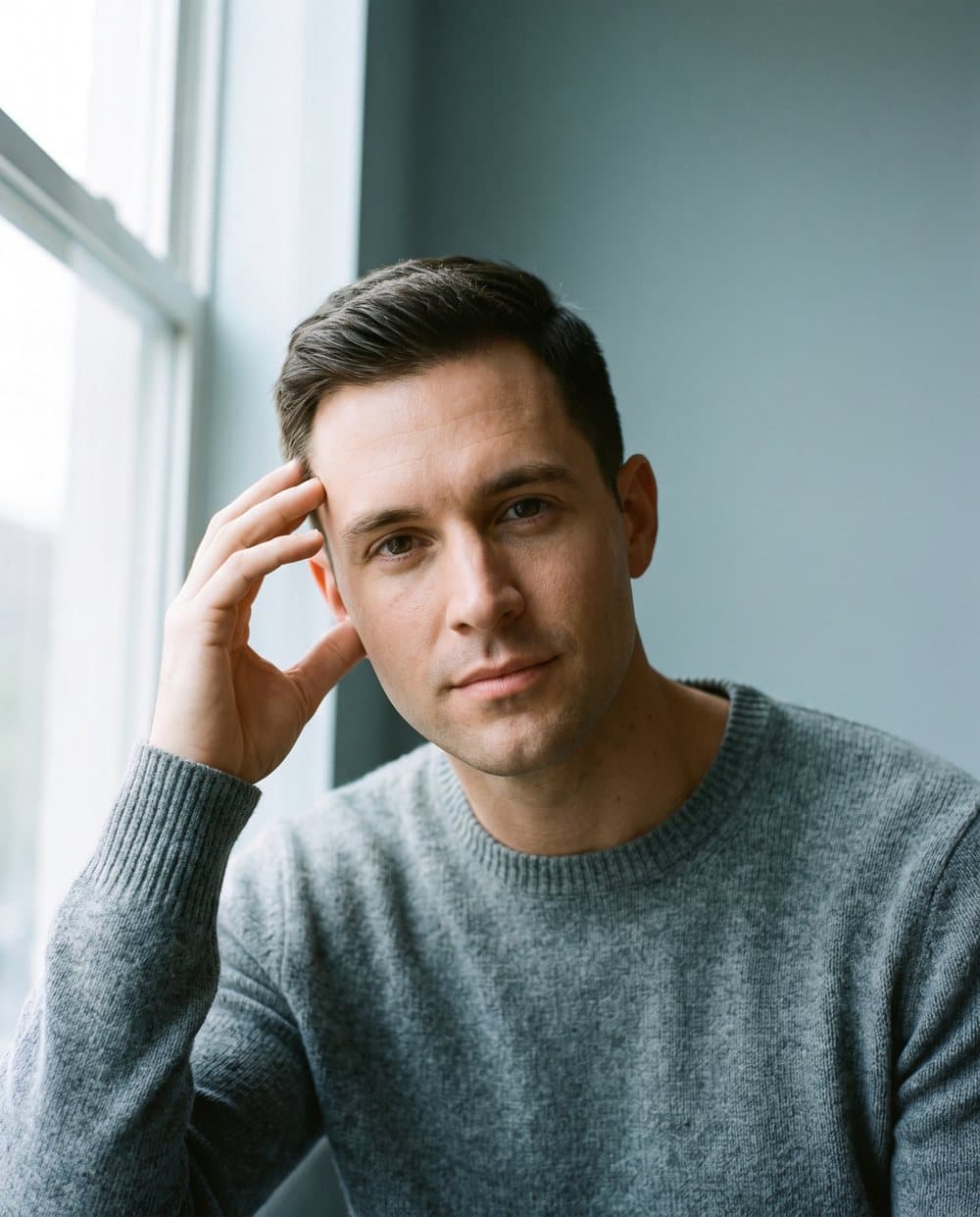 Portrait of a man touching his temple and hairline